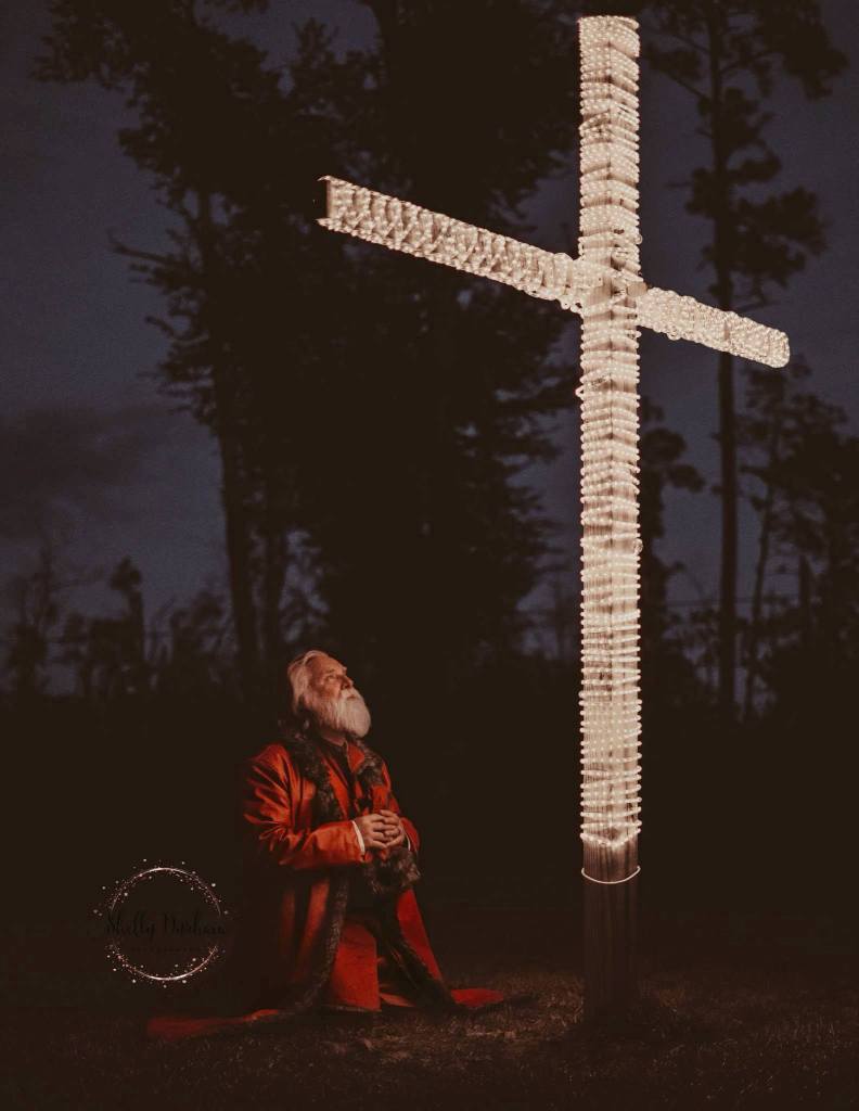 Santa kneeling in front of cross